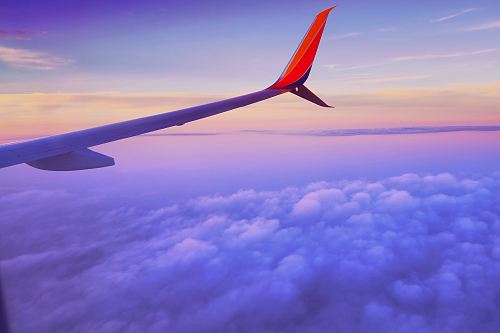 person in a plane flying at high altitude taking photo of left airplane wing during daytime