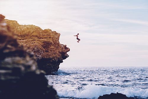 person jumping to body of water during daytime