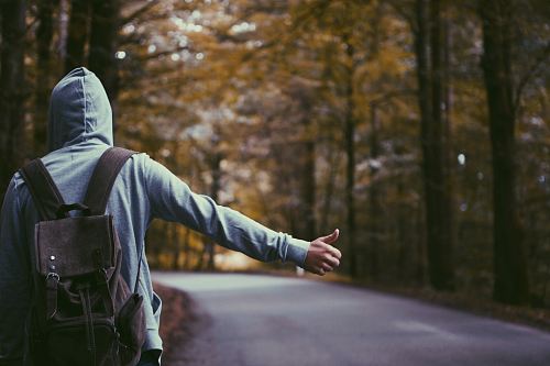 person standing beside road doing handsign