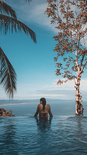 woman wearing black bikini tap swimming on body of water between trees