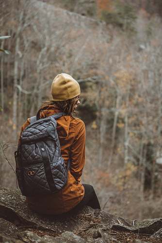woman woman sitting on rock looking sideways outdoors tree