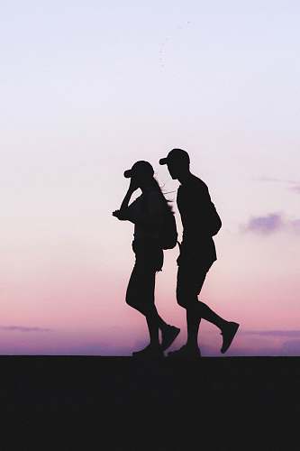 person silhouette photo of man and woman wearing caps silhouette