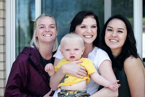 people woman carrying baby with two ladies beside her smiling person
