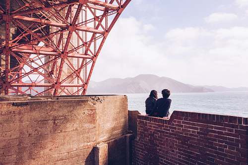 human man and woman sitting in bricked wall during daytime person