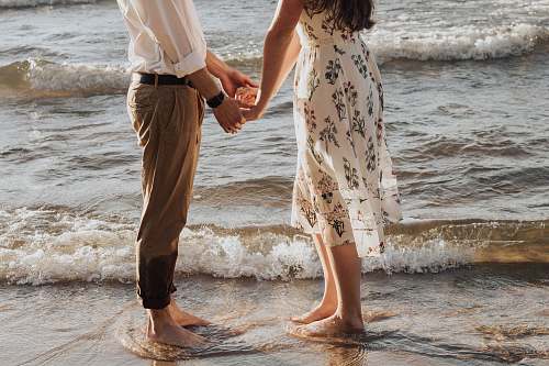 human woman holding hands in front of man standing on seashore person