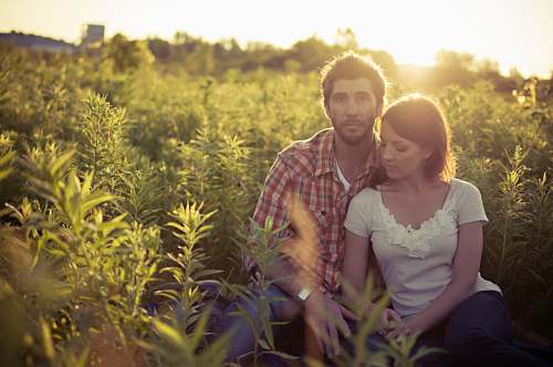 plant man and woman sitting on grass field at daytime human