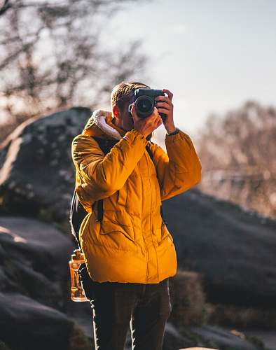 human man taking picture near gray rock people