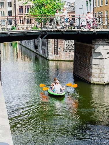 water two people kayaking under bridge boat