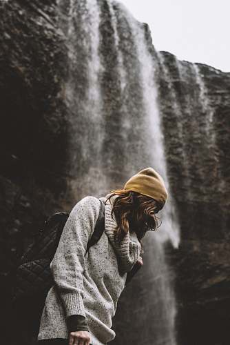 water woman in knit cap standing near waterfalls woman