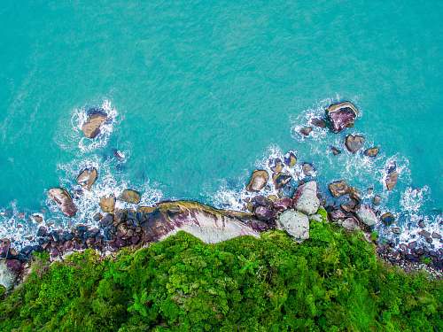 nature green and gray cliff near body of water in high angle photography water