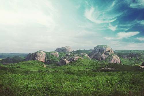 landscape rocks surrounded by green field under blu sky rocks