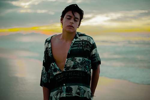 shirt man wearing black and teal shirt on sea shore beach
