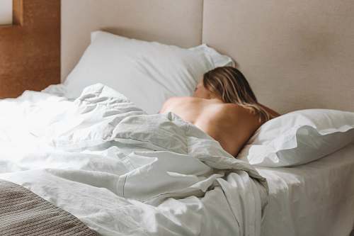 sleeping naked woman lying on bed during daytime furniture
