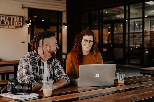person man and woman sitting in front of silver macbook human