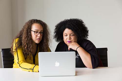 person two women looking at the screen of a MacBook human