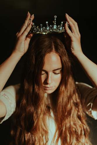 person woman putting silver-colored tiara on her head royal