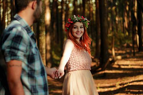 human couple holding hands while standing near tree barks person