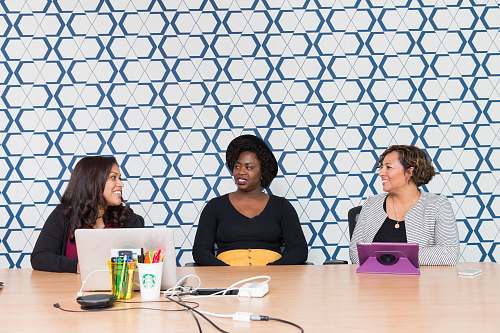 human three women sitting on chairs front of table sitting