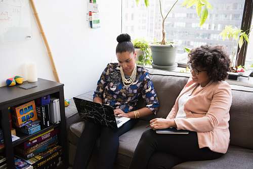 human two woman siting on sofa inside room sitting