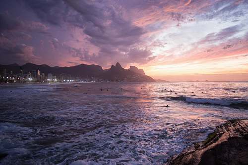 backgrounds white buildings beside seashore behind mountain under thick clouds wallpapers