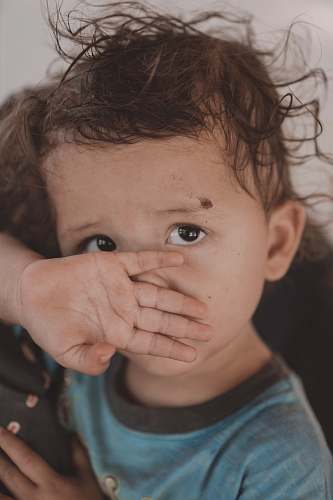 human toddler covering their nose and mouth with their hand person