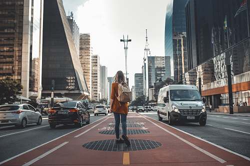 person photography of woman walking in between road with vehicles people