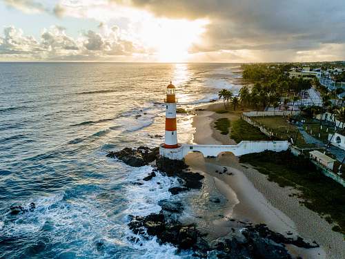 water white and orange lighthouse beside sea sea