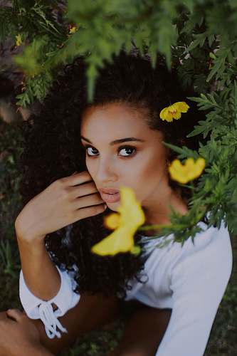 person women's white scoop-neck long-sleeved blouse beside yellow petaled flower plants during daytime human