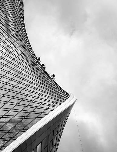 building grayscale photo of men climbing on building office building