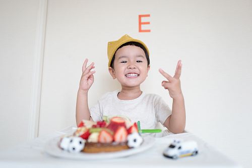 boy in front of cake and white car toy