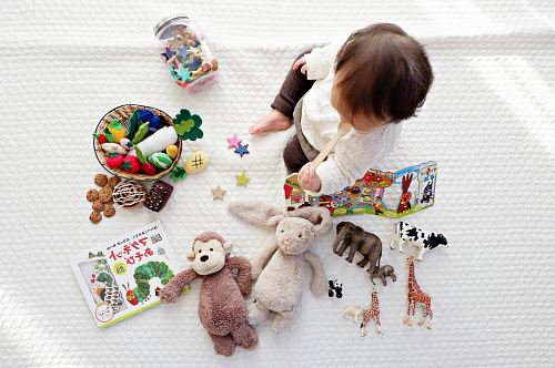 boy sitting on white cloth surrounded by toys
