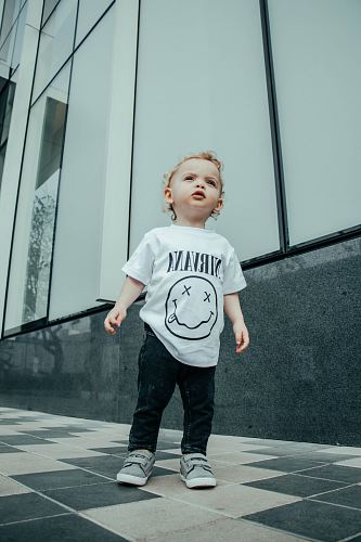 child in Nirvana shirt standing near building