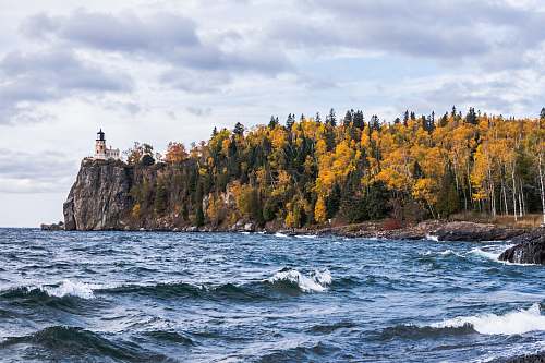 sea body of water near island with trees and lighthouse water
