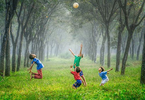 four boy playing ball on green grass
