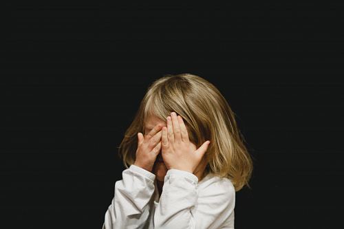 girl covering her face with both hands