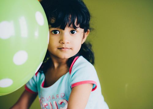 girl holding green balloon