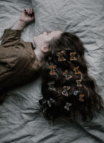 girl lying on gray bed sheet