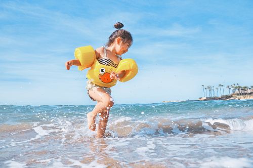 girl playing beside body of water during daytime