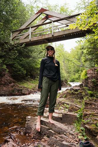 person woman in black jacket standing on brown wooden bridge outdoors