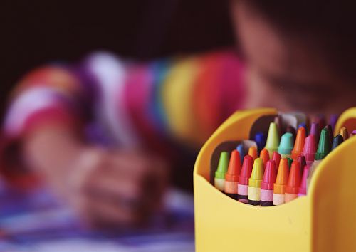 selective focal photo of crayons in yellow box
