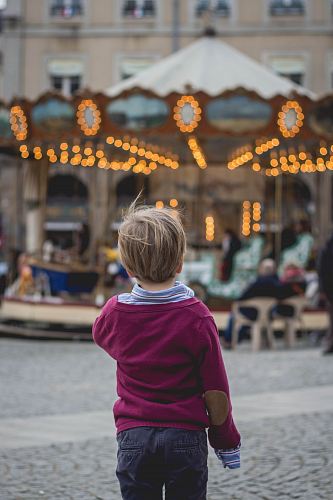 selective focus photography of boy standing in front of carousel