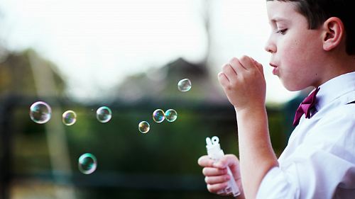 selective photography of boy playing with bubbles