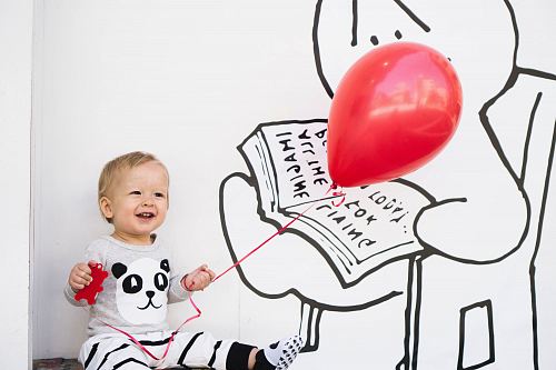 smiling toddler holding red balloon