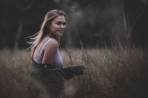 smiling woman standing on brown grass