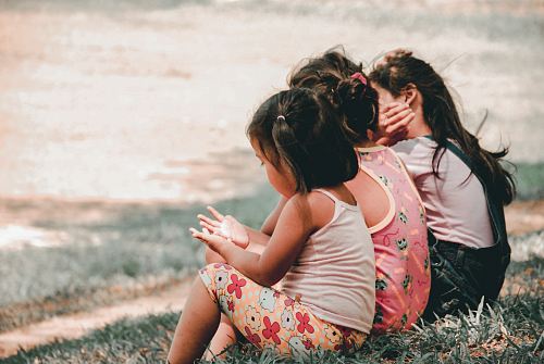 three children sitting on grass
