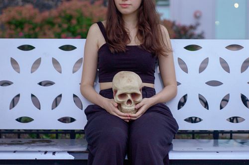 woman holding skull sitting on bench