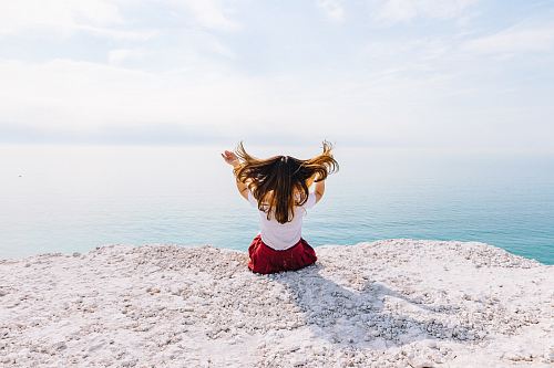 woman sitting on cliff near body of water