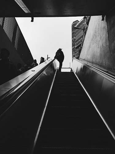 banister silhouette of person standing beside escalator during daytime handrail