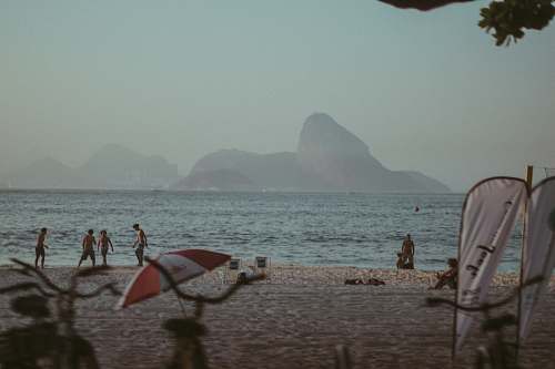 coast people standing beside sea under gray sky beach