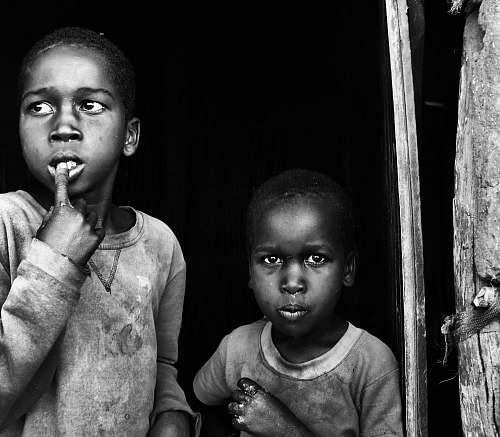 people closeup photo of two children near wall black-and-white
